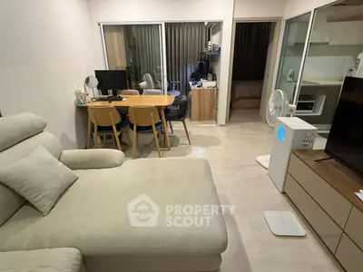 Modern living room with cozy sofa, dining area, and open view to bedroom and kitchen.
