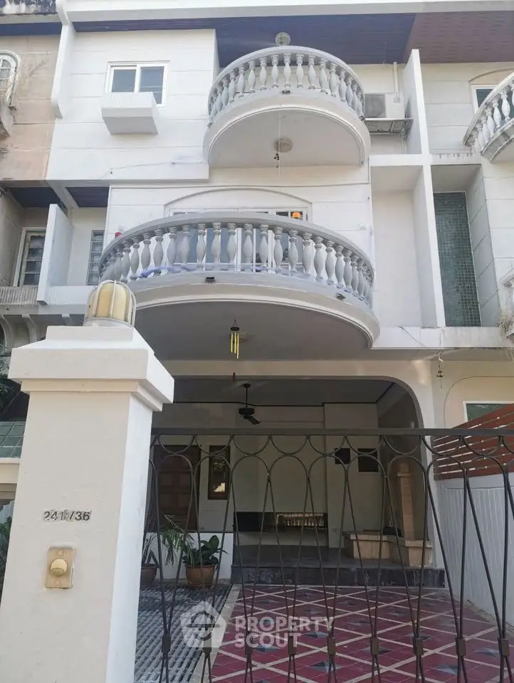 Elegant multi-story building with distinctive balconies and gated entrance, perfect for urban living.