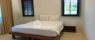 Cozy bedroom with large bed and natural light from windows, perfect for relaxation.