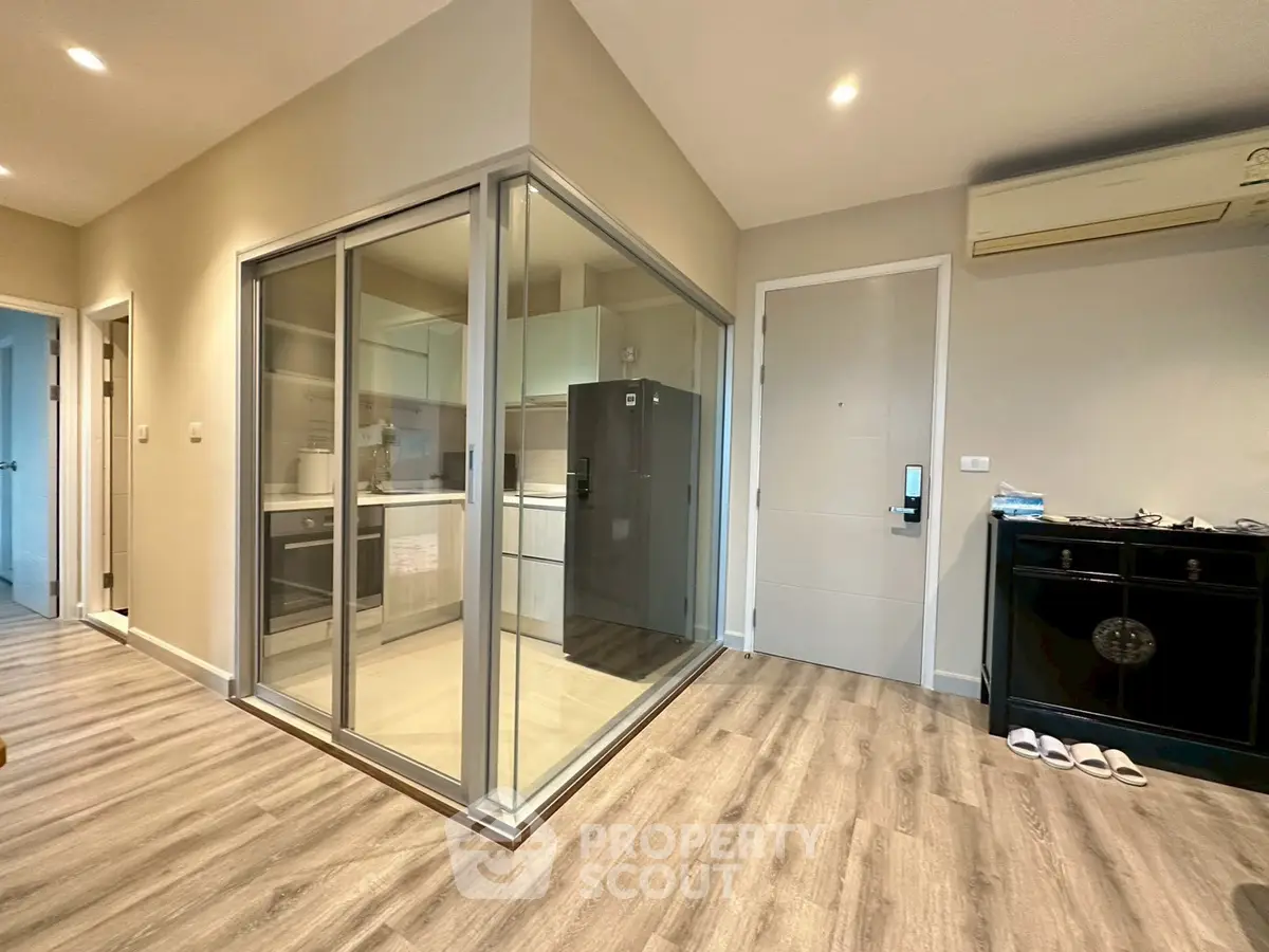 Modern apartment interior with glass-enclosed kitchen and sleek flooring