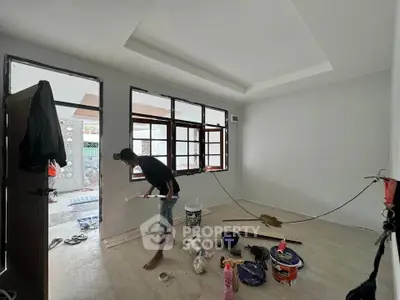 Spacious room under renovation with open windows and painting supplies