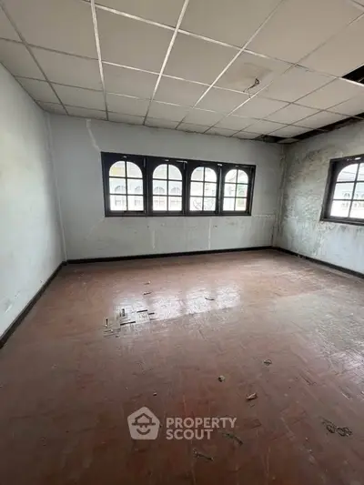 Spacious room with large windows and tiled floor, ideal for renovation.
