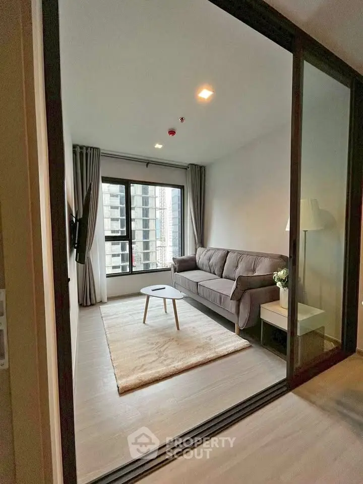 Modern living room with cozy sofa and large window in high-rise apartment