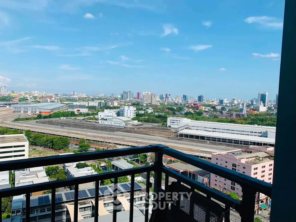 Stunning cityscape view from a high-rise balcony overlooking urban skyline and railway tracks.