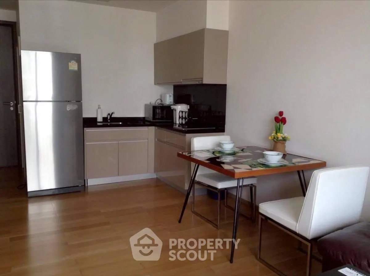 Modern kitchen with dining area, featuring sleek cabinets and stainless steel appliances.