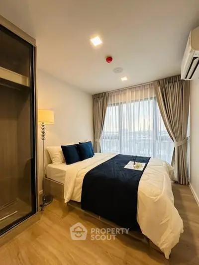 Modern bedroom with elegant decor and large window offering natural light.