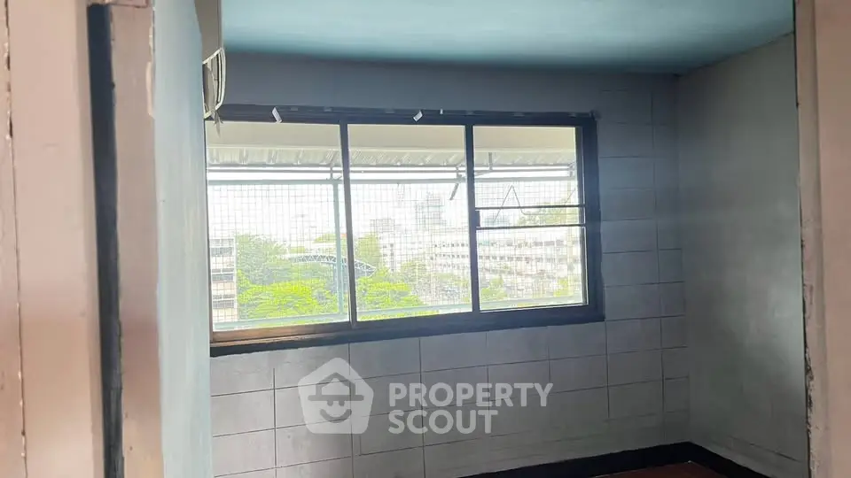 Spacious room with large window offering cityscape views, ideal for natural light and urban living.