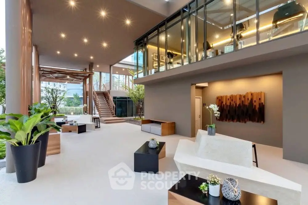 Luxurious modern building entrance with stylish decor and ample natural light, featuring elegant seating and greenery.