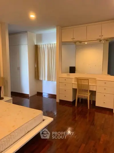 Spacious bedroom with wooden flooring and built-in vanity desk, ideal for modern living.