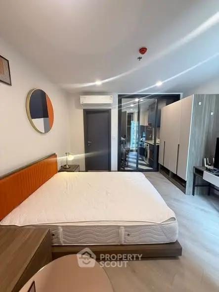 Modern bedroom with stylish decor and open layout leading to kitchen area.