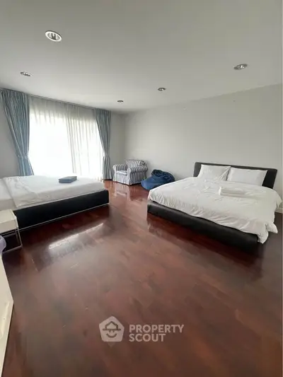 Spacious bedroom with two large beds and elegant wooden flooring.