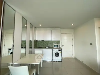 Modern kitchen with sleek white cabinets, washing machine, and stylish backsplash in a compact open layout.