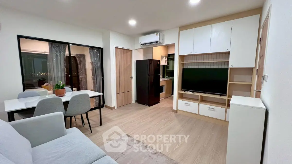 Modern living room with open kitchen, sleek furniture, and ambient lighting.