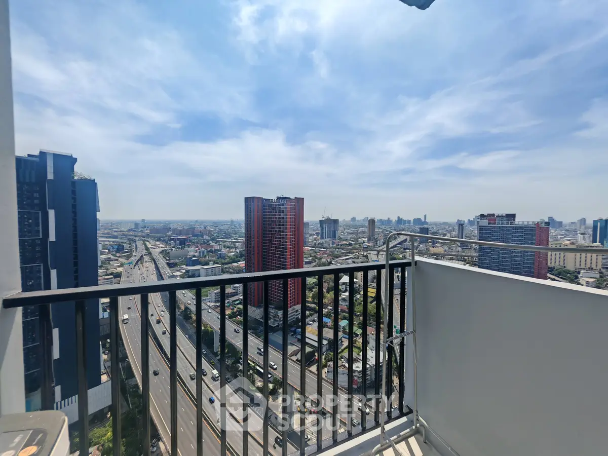 Stunning cityscape view from a high-rise balcony overlooking urban skyline and highway.