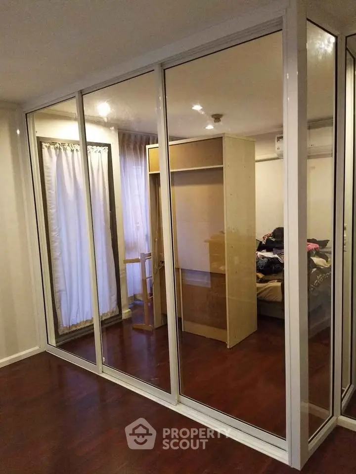 Spacious bedroom with mirrored closet doors and wooden flooring