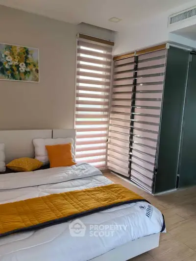 Modern bedroom with stylish blinds and cozy bedding in a well-lit space.