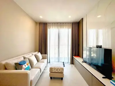 Modern living room with cozy sofa and large TV, featuring elegant curtains and bright lighting.