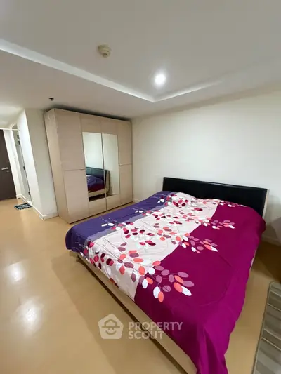 Spacious bedroom with modern wardrobe and vibrant bedding in a stylish apartment.