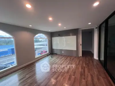 Spacious modern room with large windows and wooden flooring, ideal for office or living space.