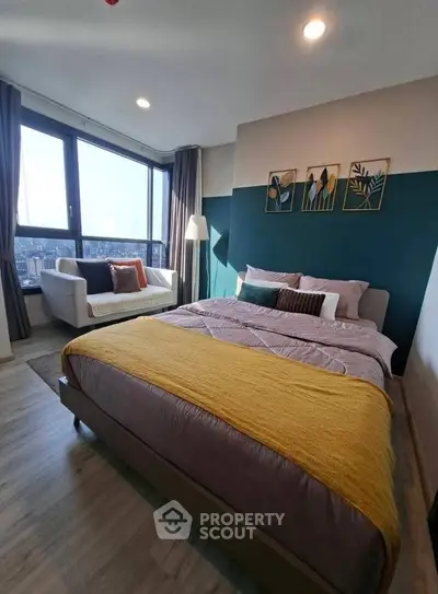 Modern bedroom with city view, stylish decor, and cozy seating area.