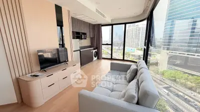 Modern living room with floor-to-ceiling windows and city view, featuring sleek furniture and integrated kitchen appliances.