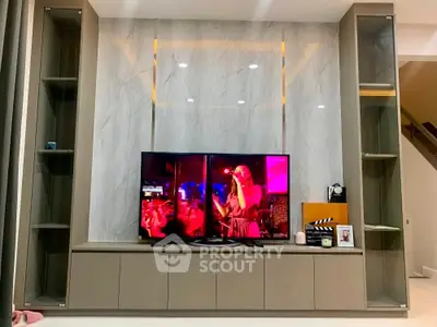 Modern living room with sleek entertainment center and large TV display.
