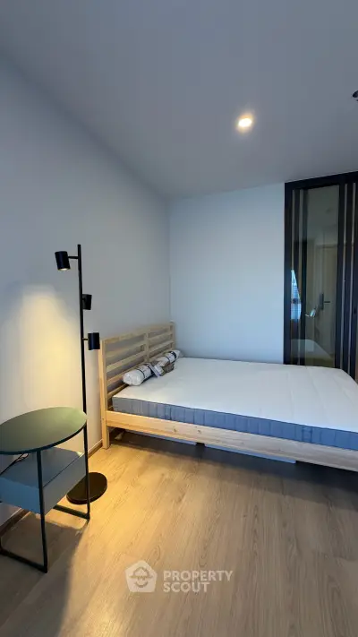 Modern minimalist bedroom with wooden flooring and stylish lighting