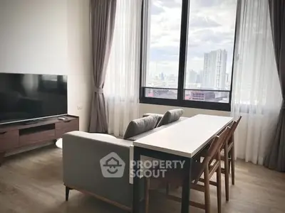 Modern living room with city view, large windows, and stylish furniture.