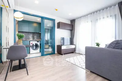 Modern living room with open kitchen and washing machine, stylish decor and natural light.