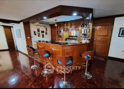 Luxurious home bar with wooden finish and modern bar stools in elegant living space.