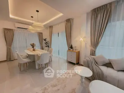 Elegant living room with modern dining area, featuring chic lighting and plush furnishings in a cozy setting.