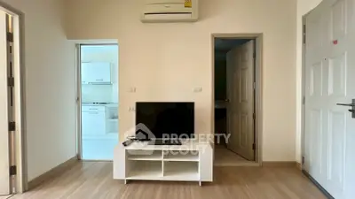 Modern living room with TV stand and air conditioning, adjacent to a bright kitchen.