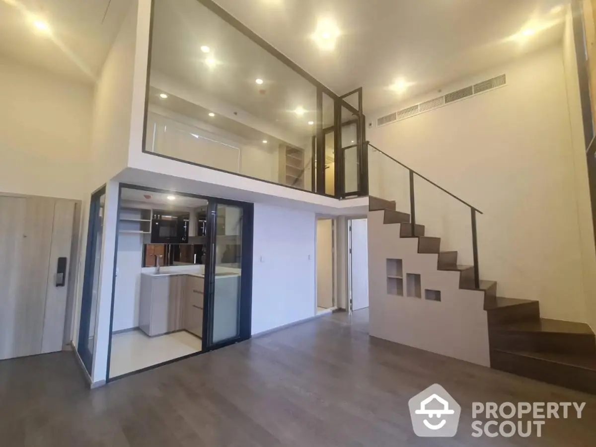 Spacious multi-level home with high ceilings, modern kitchen, and elegant staircase leading to an upper floor with glass balustrades, perfect for luxurious living.