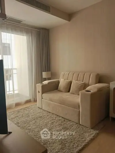 Cozy living room with beige sofa and natural light from balcony window.