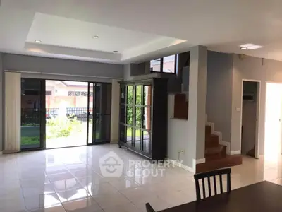 Spacious living room with large windows and garden view, featuring modern furniture and elegant design.