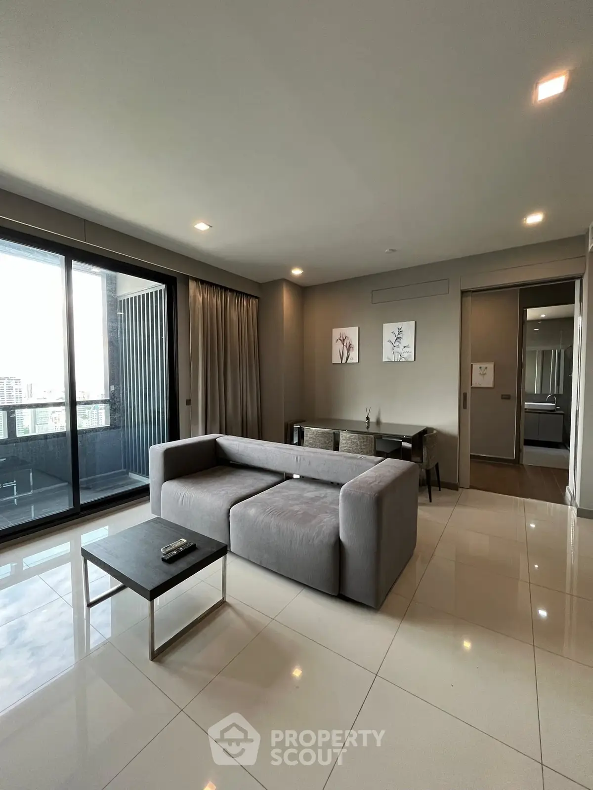 Spacious modern living room with sleek furniture and large windows offering city views.