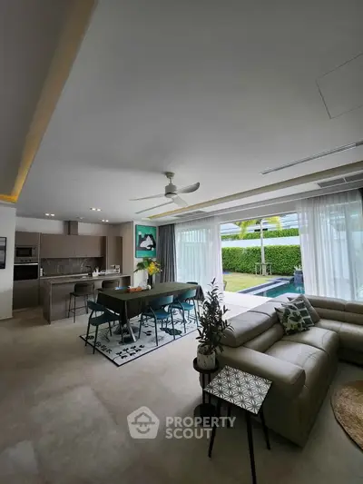 Luxurious open-plan living room with pool view and modern kitchen