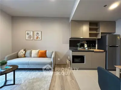 Modern living room with stylish kitchen, featuring sleek appliances and cozy seating area.