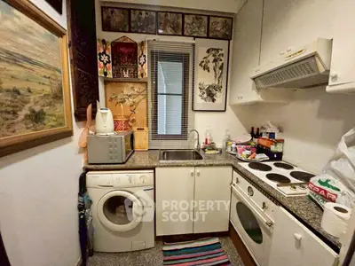 Cozy kitchen with washing machine and electric stove in compact layout