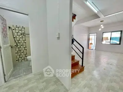 Spacious interior with tiled flooring and modern staircase, featuring a bathroom and open living area.
