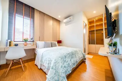 Modern bedroom with stylish decor, wooden flooring, and natural light from large window.