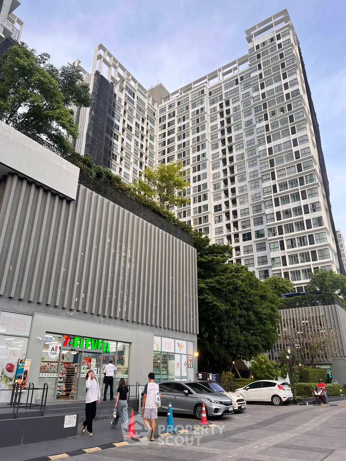 Modern high-rise building with retail shops and parking area, showcasing urban living convenience.