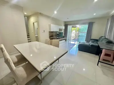 Spacious modern living room with dining area and large windows opening to a balcony.