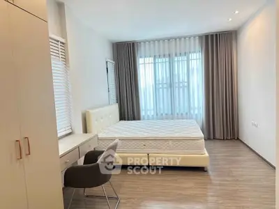 Spacious modern bedroom with large windows and elegant furnishings.