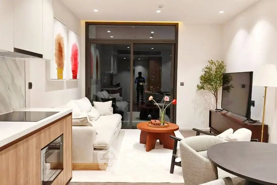 Modern living room with stylish decor and large TV, featuring open layout and cozy seating area.