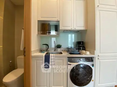 Compact kitchen with washing machine and modern appliances in cozy apartment.