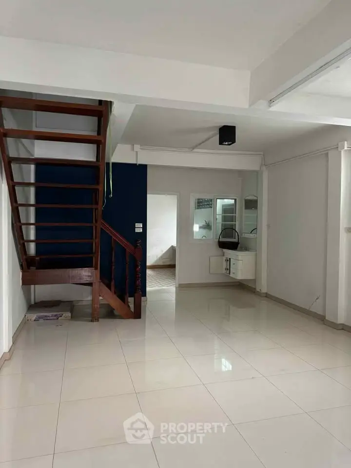 Spacious open-plan living area with modern staircase and tiled flooring