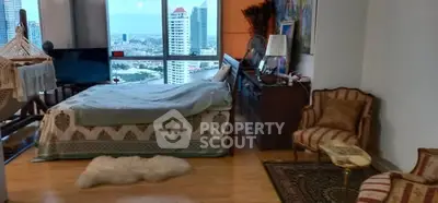 Spacious bedroom with city view, elegant decor, and cozy seating area.