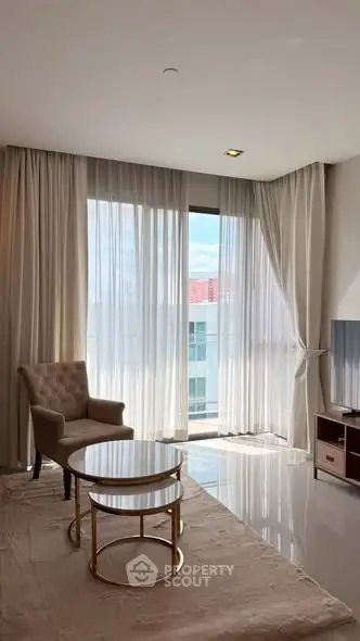 Elegant living room with modern furniture and large windows offering natural light and city views.