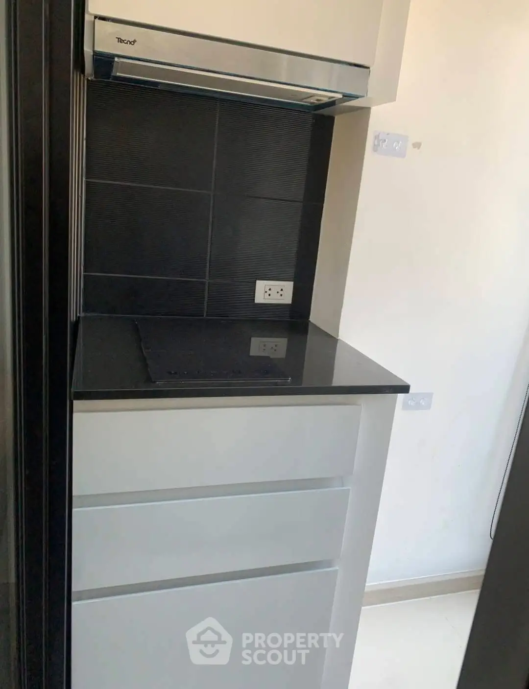 Modern compact kitchen with sleek black countertop and built-in stove, ideal for urban living.